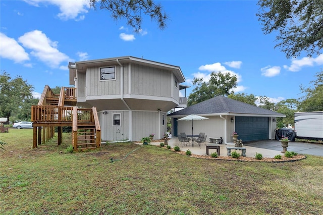 rear view of property with a garage, a yard, and a patio