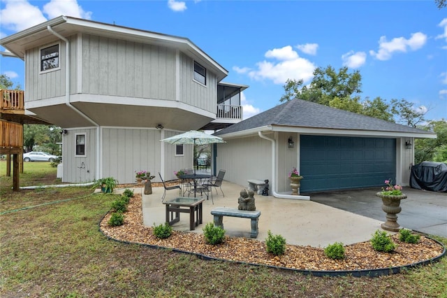 rear view of property with a balcony, a garage, and a patio area