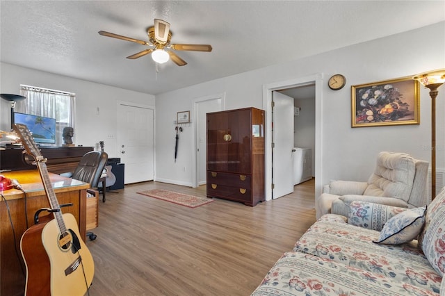 living room featuring ceiling fan, hardwood / wood-style floors, a textured ceiling, and washer / dryer