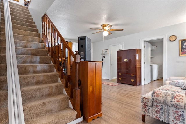 stairs featuring hardwood / wood-style floors, ceiling fan, washer / dryer, and a textured ceiling