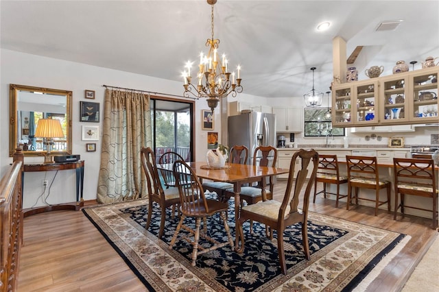 dining space with sink, light hardwood / wood-style flooring, and an inviting chandelier