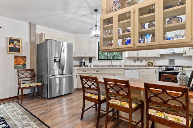 kitchen featuring hanging light fixtures, stainless steel appliances, ventilation hood, wood-type flooring, and white cabinets