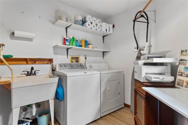 laundry room featuring washing machine and dryer, light hardwood / wood-style flooring, and sink