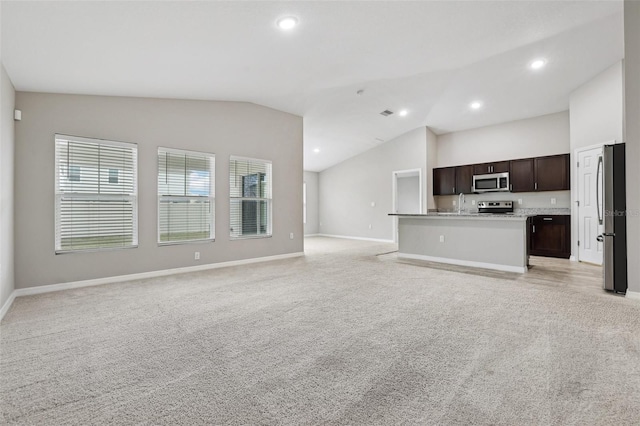 unfurnished living room with light colored carpet, vaulted ceiling, and sink