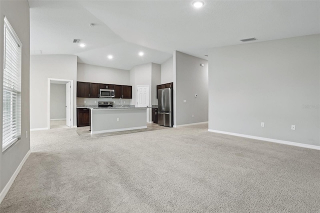 unfurnished living room with light colored carpet, high vaulted ceiling, and sink