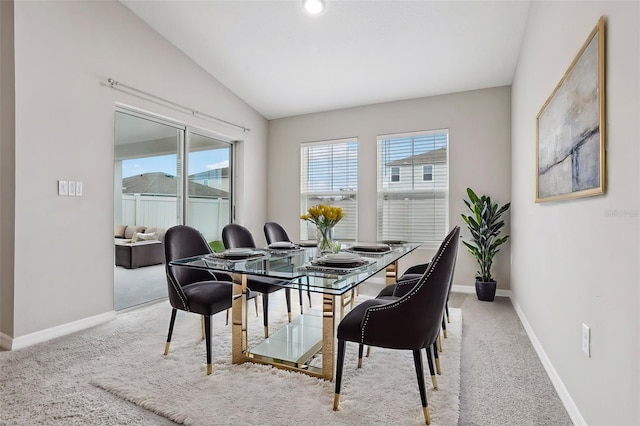 dining room featuring light colored carpet and lofted ceiling