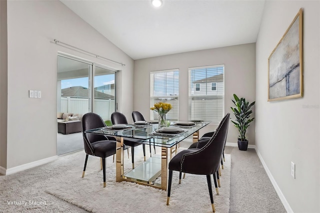 carpeted dining area with vaulted ceiling