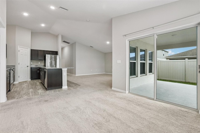 unfurnished living room with light carpet and vaulted ceiling