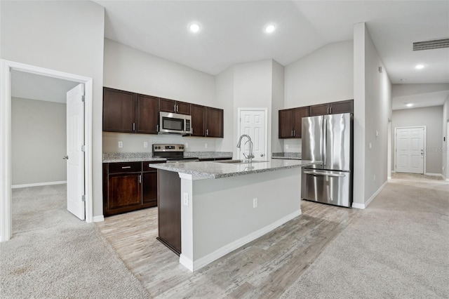 kitchen featuring dark brown cabinetry, sink, stainless steel appliances, high vaulted ceiling, and a center island with sink