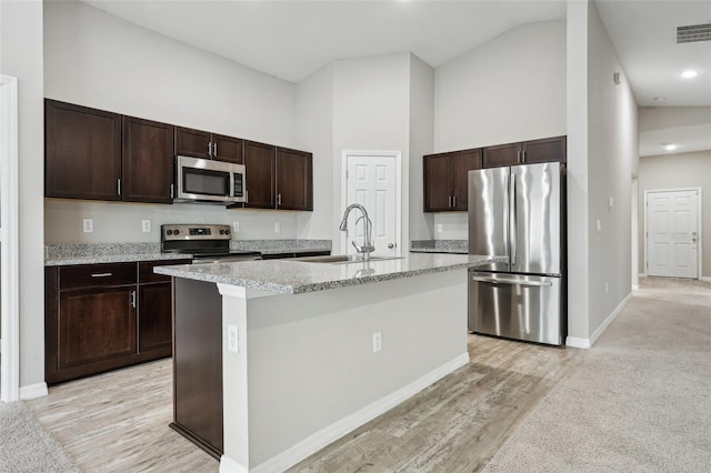 kitchen featuring sink, high vaulted ceiling, a kitchen island with sink, dark brown cabinets, and appliances with stainless steel finishes