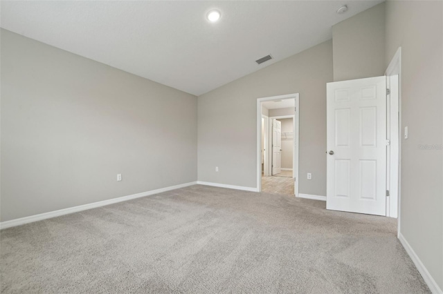 unfurnished bedroom with light colored carpet and lofted ceiling