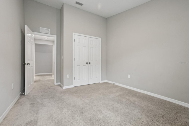 unfurnished bedroom with light carpet, a closet, and a high ceiling