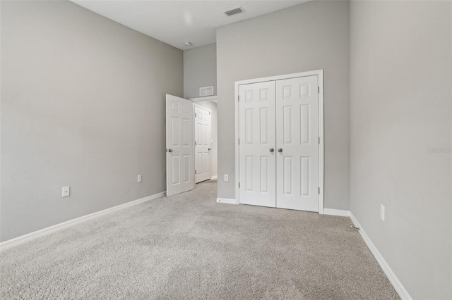 unfurnished bedroom featuring a high ceiling, light colored carpet, and a closet