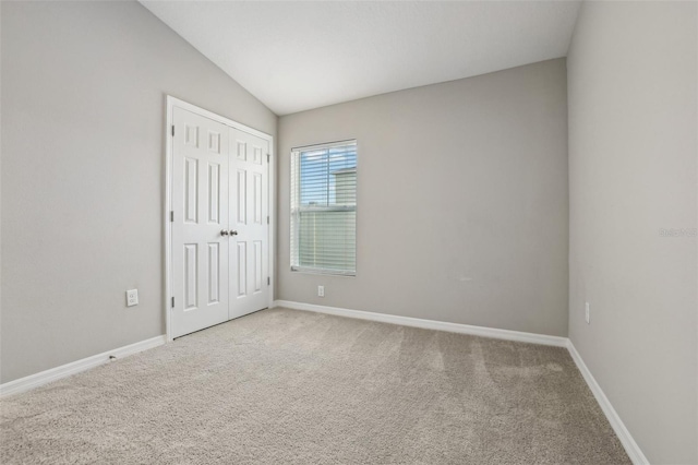 carpeted empty room with lofted ceiling