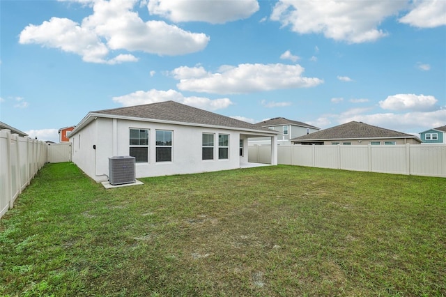 rear view of property featuring a lawn and central air condition unit