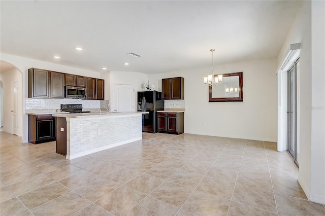 kitchen with an inviting chandelier, backsplash, an island with sink, decorative light fixtures, and black appliances