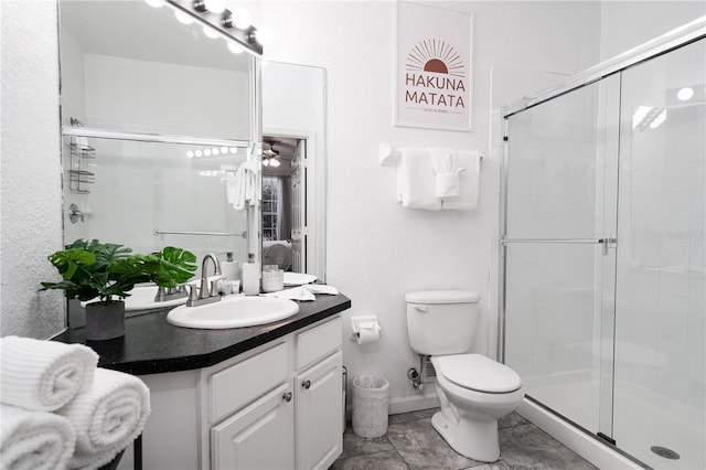 bathroom with vanity, toilet, a shower with door, and ceiling fan