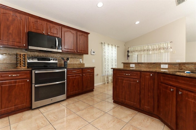 kitchen with tasteful backsplash, dark stone counters, lofted ceiling, light tile patterned floors, and appliances with stainless steel finishes