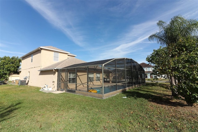 rear view of house featuring central air condition unit, glass enclosure, and a lawn