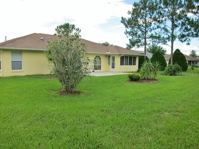 rear view of property featuring a yard and a patio