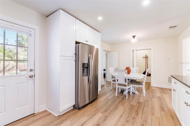 kitchen featuring white cabinetry, dark stone counters, light hardwood / wood-style floors, and stainless steel fridge with ice dispenser