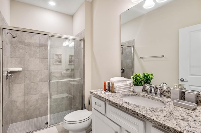 bathroom featuring vanity, a shower with shower door, and toilet