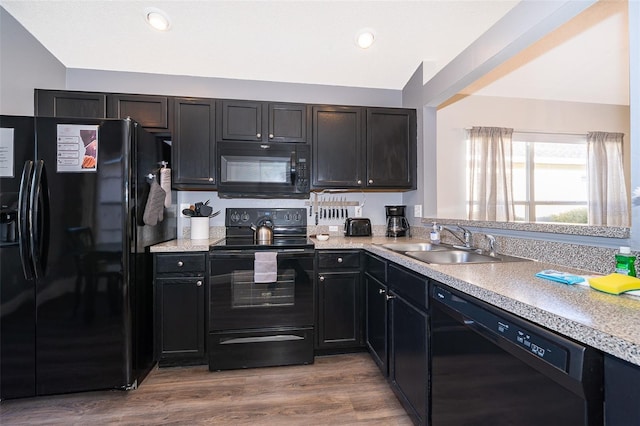 kitchen with black appliances, light wood-type flooring, and sink