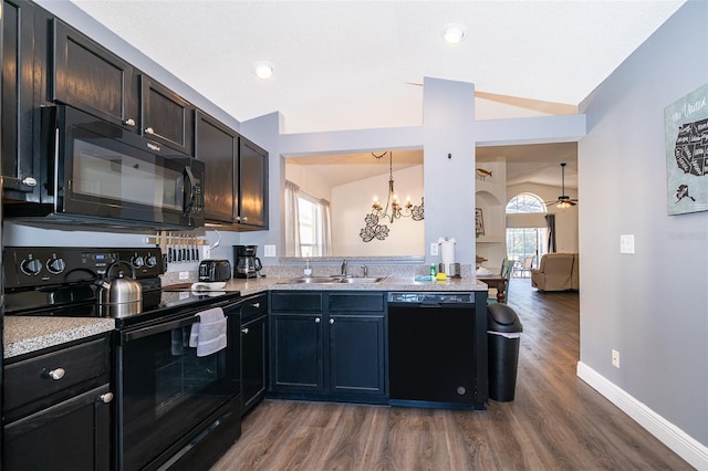 kitchen featuring pendant lighting, lofted ceiling, dark wood-type flooring, black appliances, and ceiling fan with notable chandelier