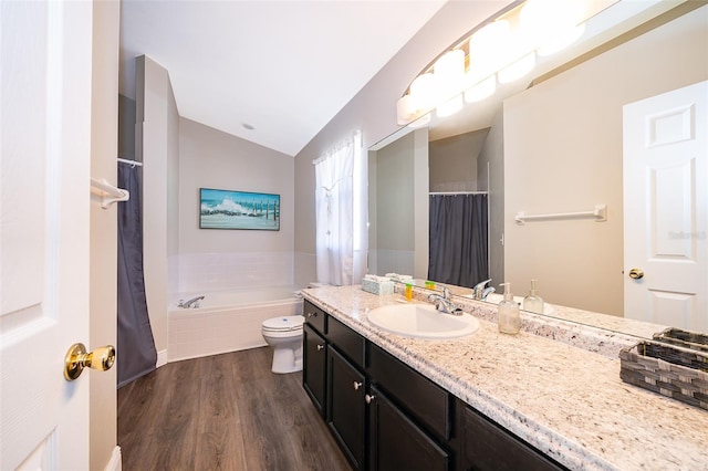 bathroom with vanity, vaulted ceiling, a relaxing tiled tub, hardwood / wood-style floors, and toilet