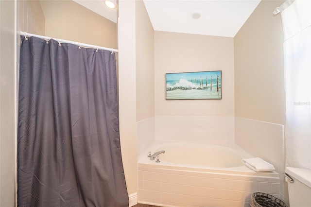 bathroom featuring a relaxing tiled tub and toilet