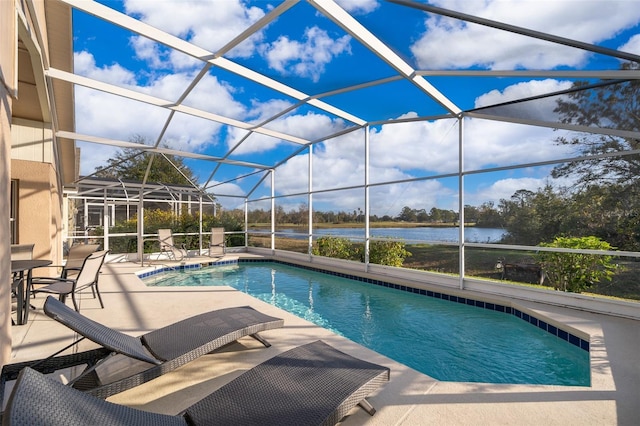 view of pool with glass enclosure, a water view, and a patio