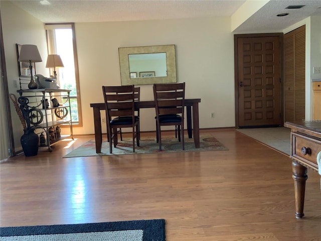 dining space featuring a textured ceiling, baseboards, and wood finished floors