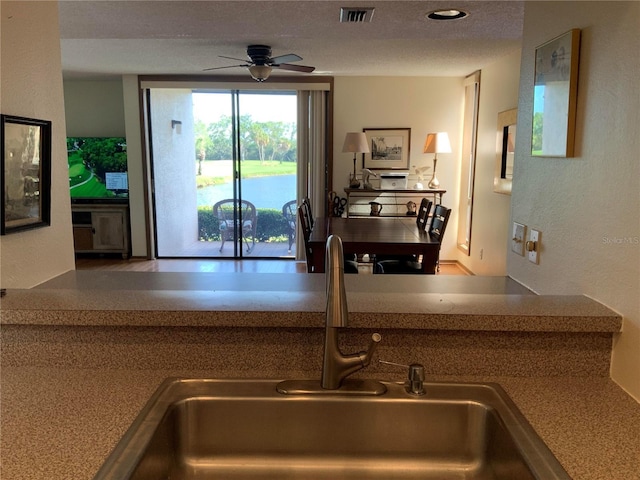 kitchen with light countertops, visible vents, a sink, a textured ceiling, and ceiling fan