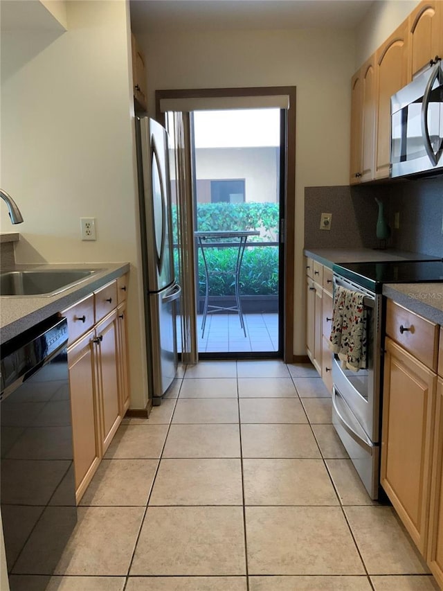 kitchen featuring stainless steel appliances, light tile patterned flooring, a sink, and light brown cabinetry