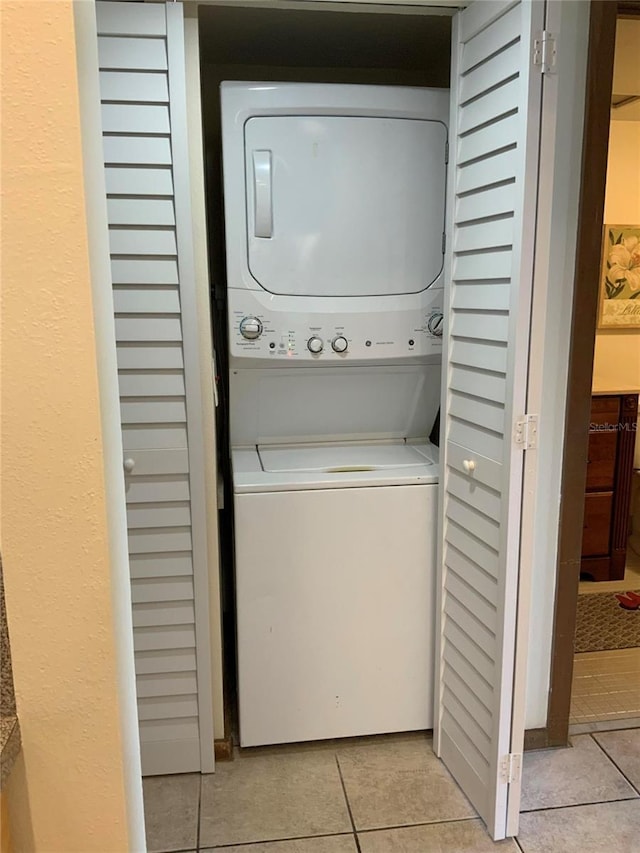 washroom with laundry area, light tile patterned flooring, and stacked washer / drying machine