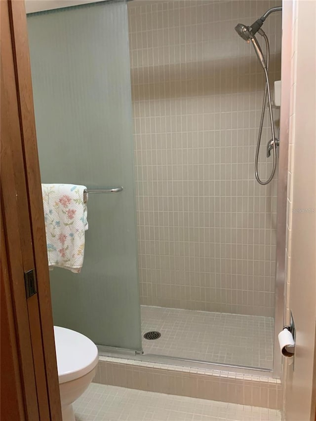 bathroom featuring a stall shower, tile patterned flooring, and toilet