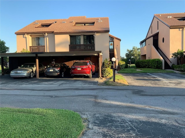 view of front of property with stucco siding, covered parking, and a tiled roof