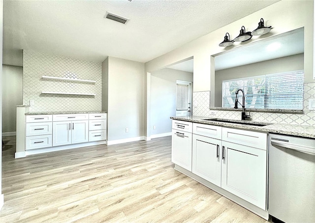 kitchen with light stone countertops, stainless steel dishwasher, sink, light hardwood / wood-style flooring, and white cabinetry