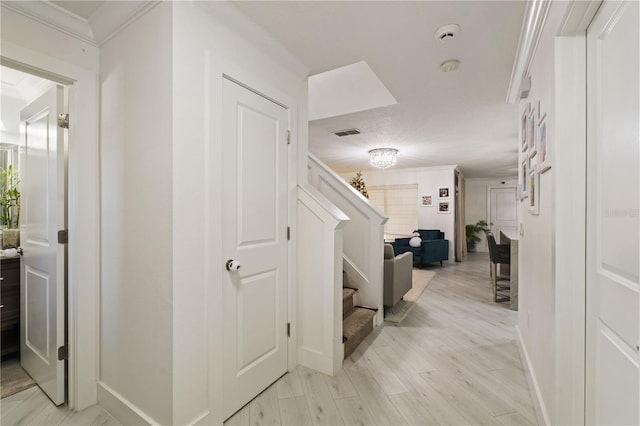 hall with light wood-type flooring and ornamental molding