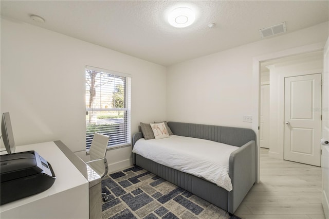 bedroom with a textured ceiling and hardwood / wood-style flooring