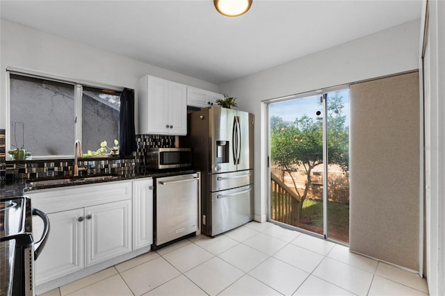 kitchen featuring dark stone counters, sink, tasteful backsplash, white cabinetry, and stainless steel appliances