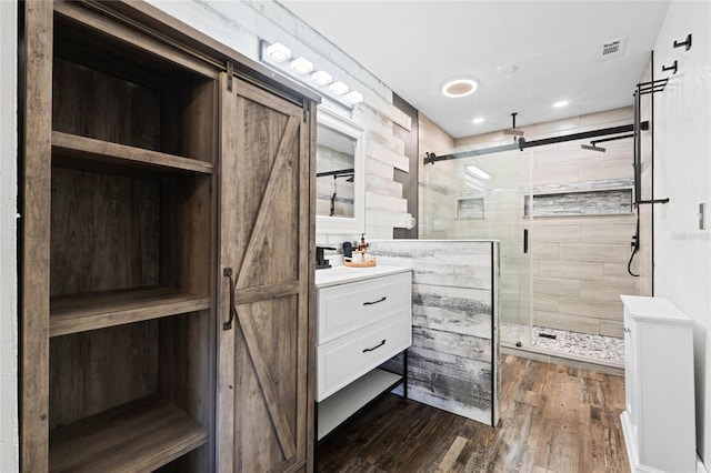 bathroom with vanity, a shower with shower door, and wood-type flooring