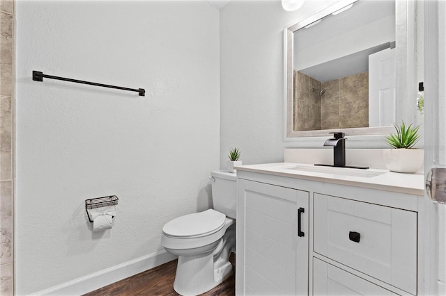 bathroom featuring wood-type flooring, vanity, toilet, and walk in shower