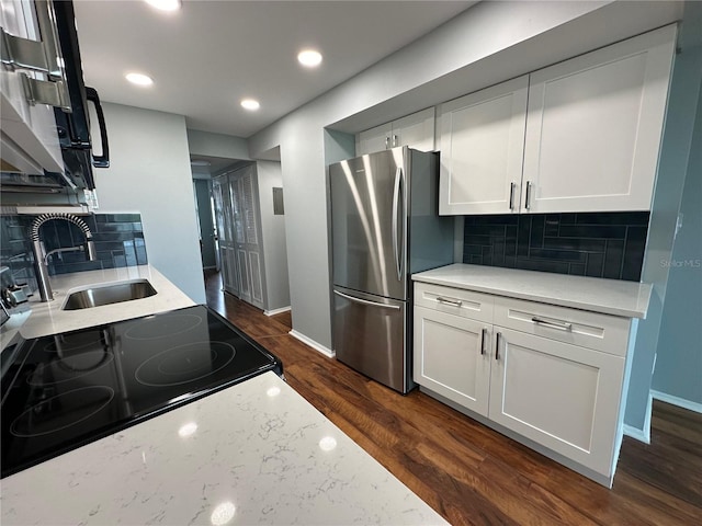 kitchen featuring stainless steel refrigerator, decorative backsplash, sink, and white cabinets