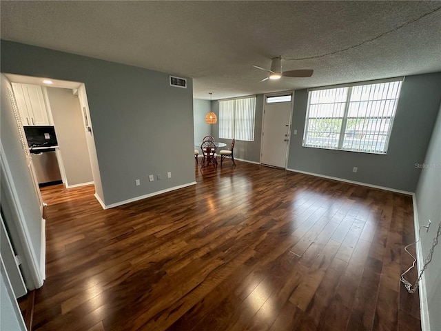 unfurnished living room featuring ceiling fan, dark wood-type flooring, and a textured ceiling