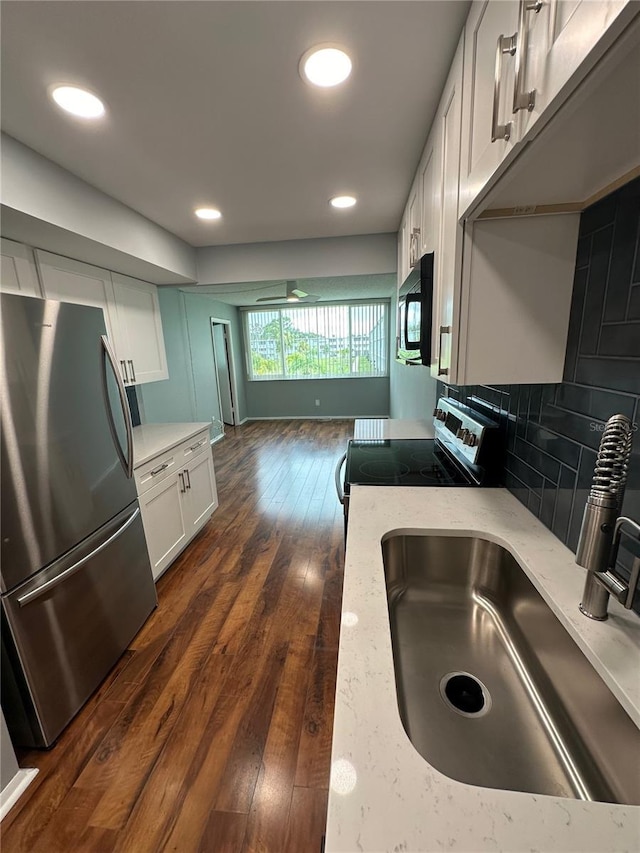 kitchen featuring stainless steel refrigerator, sink, electric stove, decorative backsplash, and white cabinets