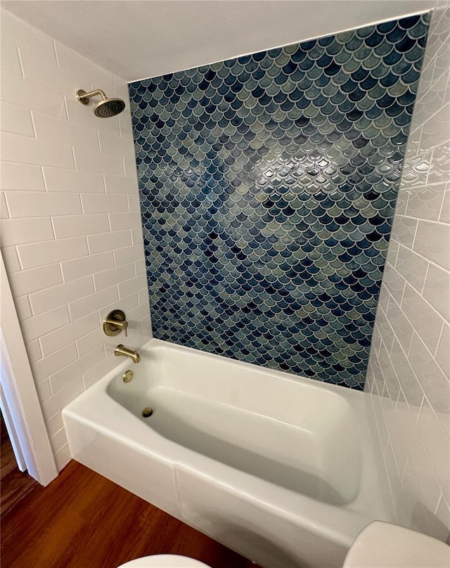 bathroom featuring toilet, wood-type flooring, and tiled shower / bath