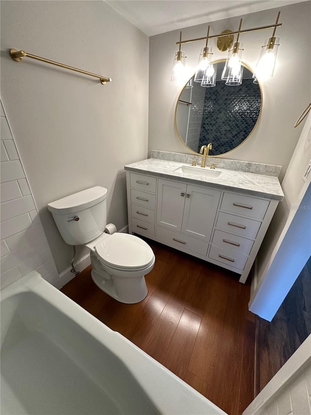 bathroom featuring wood-type flooring, vanity, toilet, and a bathing tub