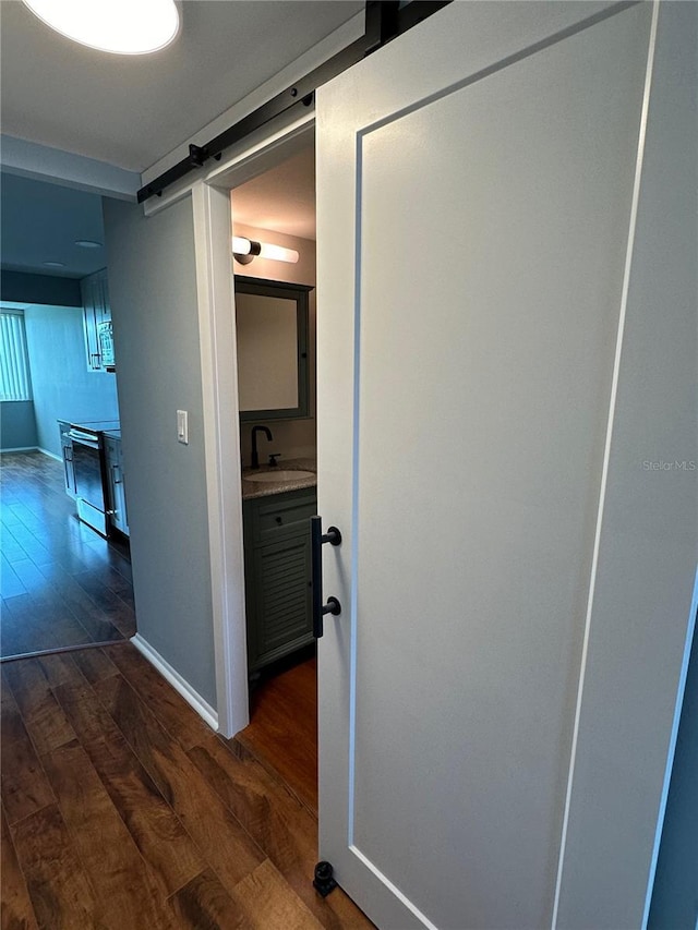 corridor with dark hardwood / wood-style floors, a barn door, and sink