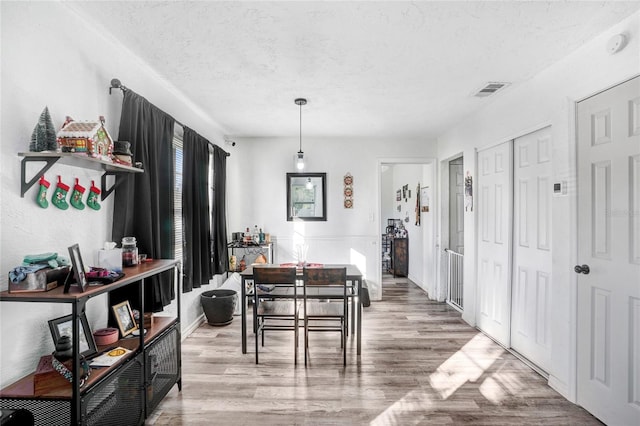 dining room with light wood-type flooring and a textured ceiling